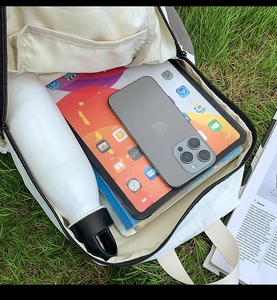 Internal view of the cream backpack showing storage for tablets, books, and water bottles