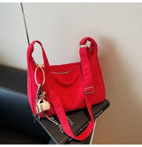 Detail of red suede hobo bag with wide strap and creative coffee cup charm