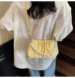 Détail du sac nuage plissé jaune crème avec chaîne de perles porté en bandoulière