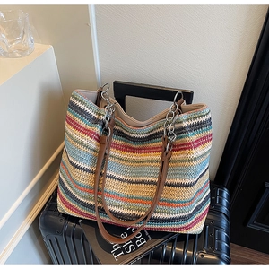 Dettaglio macro della borsa tote intrecciata a righe colorate con tracolla e catena