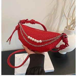 Détail du sac croissant tressé rouge avec chaîne décorative en perles et métal chic