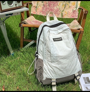 Detail of grey-white nylon outdoor backpack with side buckles on a rustic chair