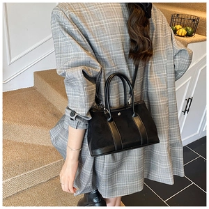 Modern black tote bag with suede texture and dual straps styled with a grey blazer