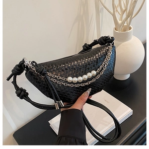 Détail du sac tressé noir avec chaînes argentées, perles et bandoulière nouée