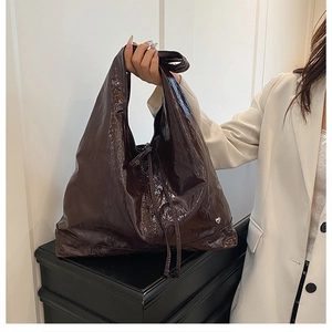 Close-up of deep brown tote bag with glossy leather texture and silver heart buckle detail