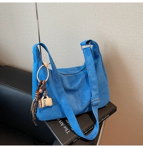 Detail of blue suede hobo bag with coffee cup charm and adjustable shoulder strap