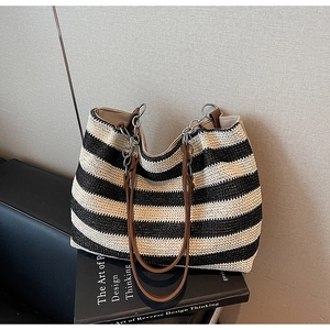 Dettaglio della borsa tote intrecciata a righe bianche e nere con manici in pelle marrone
