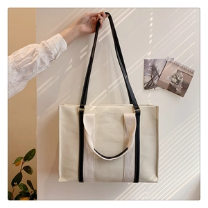 Detailed view of canvas tote bag with contrast leather straps and shadow textures