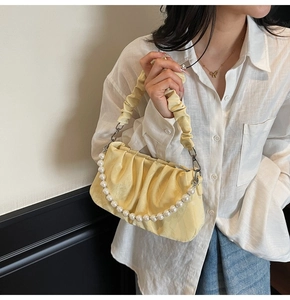 Détail du sac nuage plissé jaune avec bandoulière en perles porté par un mannequin chic