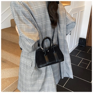 Detail of black patchwork tote bag with smooth leather and suede texture worn by model
