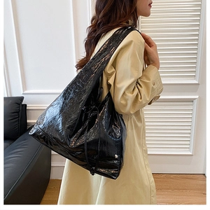 Detail view of large black tote bag featuring glossy crinkled leather and decorative ties