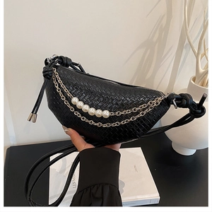 Détail d'un sac demi-lune noir tressé avec chaîne dorée et grandes perles nacrées