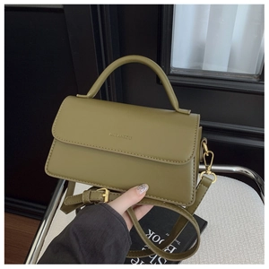 Detailed view of an olive green square crossbody bag with handle and gold hardware