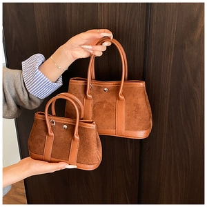 Detail view of retro caramel suede tote bag with round metal buckle and leather handle