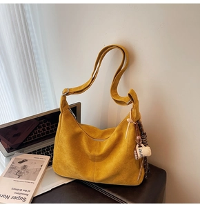 Close-up of yellow suede Hobo bag with coffee cup charm and elegant shoulder strap