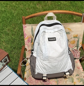 Detail of white nylon hiking backpack with FASHION label on a floral camping chair