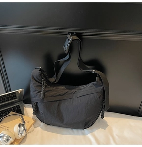 Dettaglio della borsa a tracolla in nylon nero con fibbia regolabile e tirante con cordino