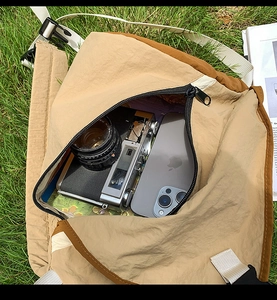 Spacious khaki nylon crossbody bag showing large capacity with camera and phone