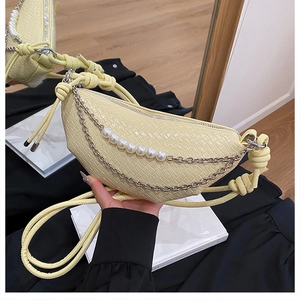 Détail du sac croissant crème avec motif crocodile et chaîne décorative en perles