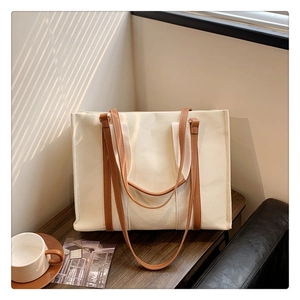 Detail of canvas tote bag with brown leather handles and double strap design