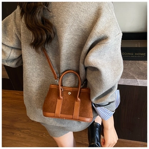 Detail of dark brown leather tote bag with top handle and silver buckle on model