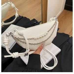 Gros plan du sac croissant en cuir tressé blanc avec perles et chaîne argentée