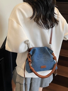 Chic blue denim bucket bag with brown leather trim and drawstring closure in street style