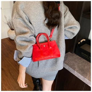 Detail of red suede mini tote with smooth leather handles and gold metal snap buckle