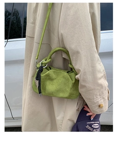 Detail of olive green suede handbag with knotted handle and black tassel ornament
