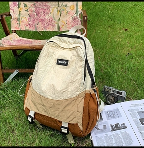 Detail of color-block nylon backpack with FASHION label on sunlit green grass