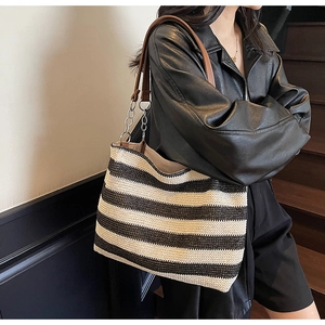 Dettaglio della borsa tote intrecciata a righe bianche e nere con manico in pelle e catena