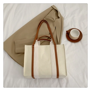 Close-up of a vintage canvas tote bag with brown leather straps on a soft beige background