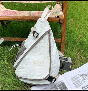 Detail view of white nylon crossbody bag featuring fashion labels and side drawstring buckles