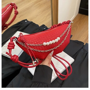 Détail du sac croissant rouge tressé avec chaîne argentée et breloques en perles