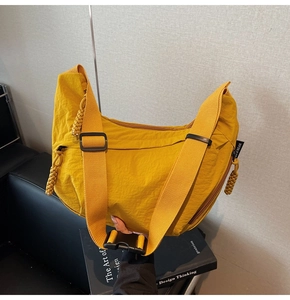 Dettaglio della borsa a tracolla a mezzaluna in nylon zenzero con ampia cinghia e zip tessuta