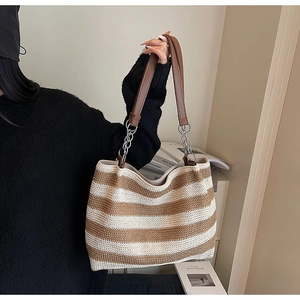 Dettaglio della borsa tote tessuta con strisce marroni e tracolla a catena in metallo