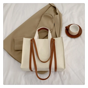 Flat lay of off-white canvas tote bag with brown straps on aesthetic fabric background
