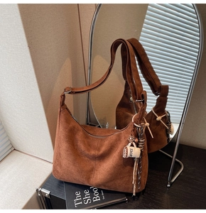 Macro detail of brown suede tote bag with coffee cup charm and adjustable wide shoulder strap