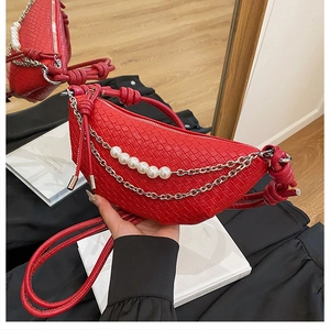 Détail du sac croissant rouge tressé avec bandoulière en perles et poignée nouée