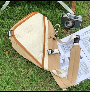 Detail of waterproof nylon crossbody bag with fashion logo on lush green grass