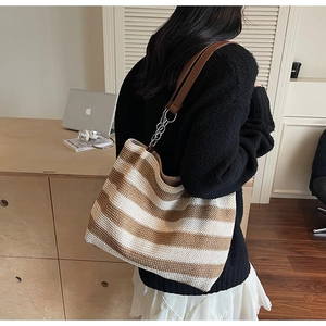 Dettaglio della borsa tote intrecciata a righe con pelle marrone e catena d'argento