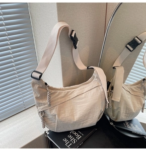 Dettaglio borsa a mezzaluna in nylon beige con cerniera intrecciata e tracolla