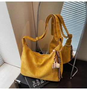 Detail view of yellow suede crescent tote bag with coffee cup charm and zip closure