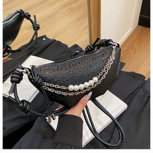 Détail du sac noir tissé avec chaîne de perles et bandoulière à nœud décoratif