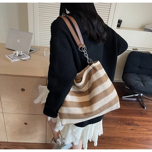 Dettaglio della borsa tote in maglia a righe beige e tracolla in pelle con catena