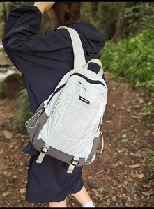 Outdoor backpack with grey and white color blocking on model in a forest path