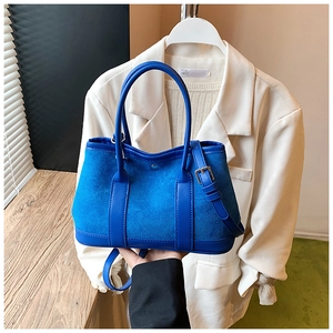 Detail view of electric blue leather tote bag showing textured stitching and handle design
