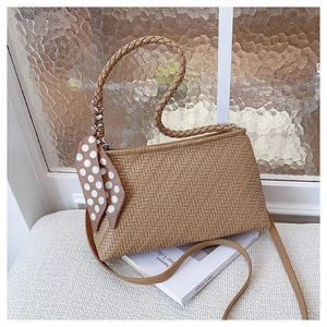 Close-up of khaki woven texture handbag with polka dot silk scarf and braided handle