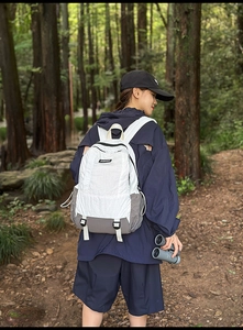 Detail of white and grey outdoor backpack featuring drawstring pockets and fashion label