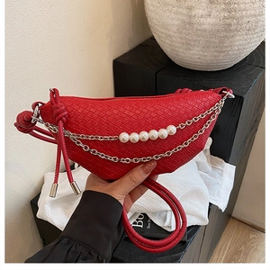 Détail d'un sac en croissant tressé rouge avec chaînes argentées et perles blanches
